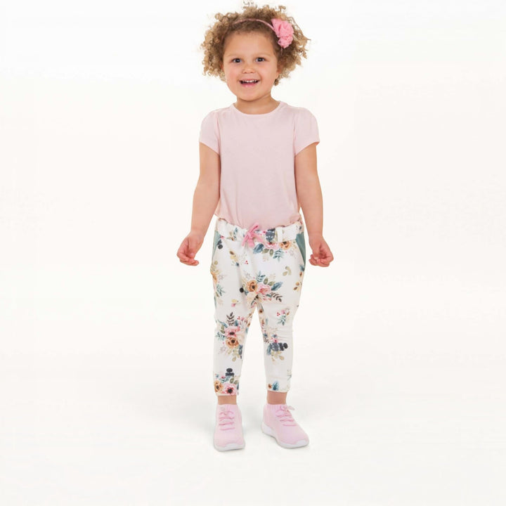 Haremshose PDF Schnittmuster DADO – Baggy Kinderhose mit Taschen 92/98–140/146, kind in floral baggy pants and pink top.