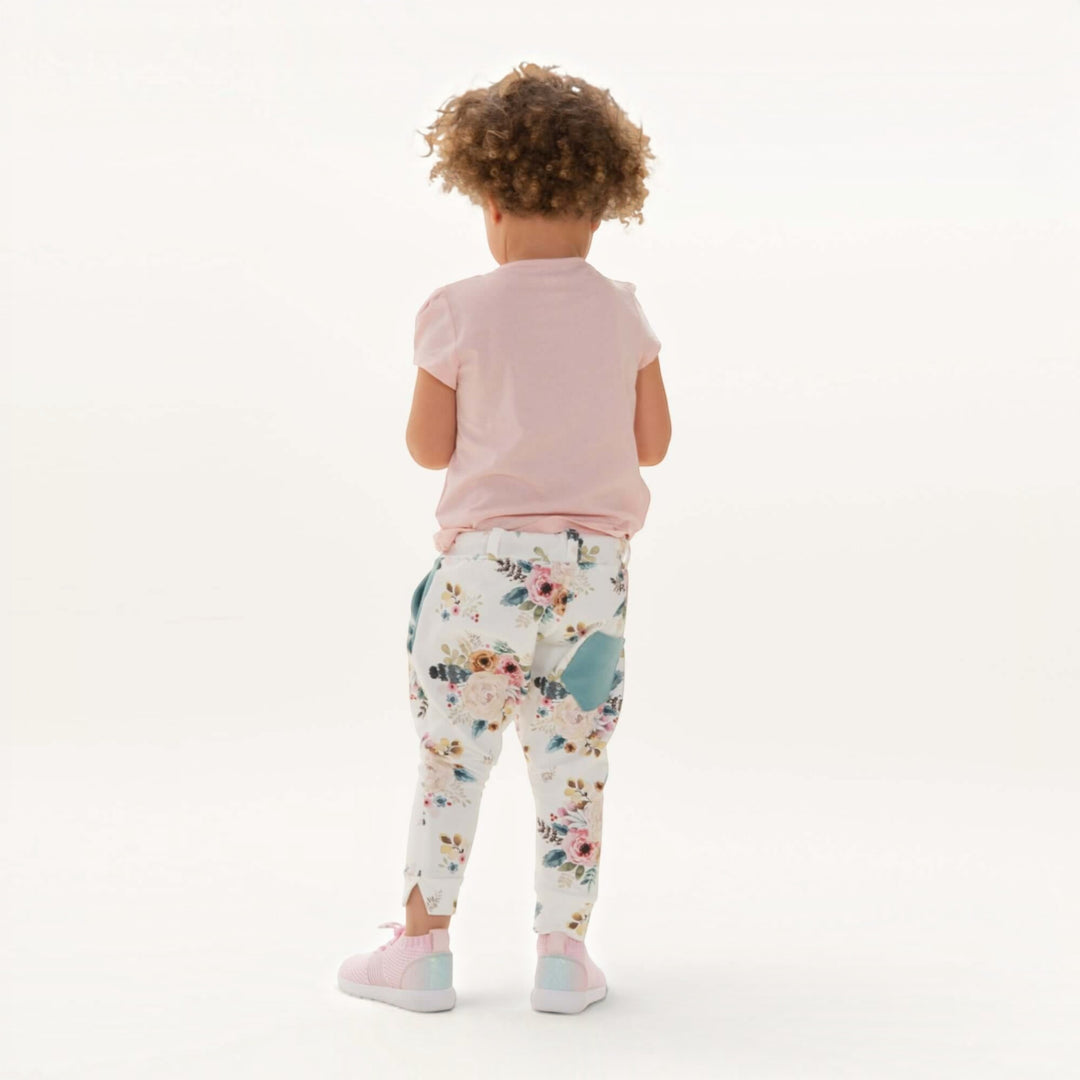 Haremshose PDF Schnittmuster DADO – Baggy Kinderhose mit Taschen 92/98–140/146, hintenansicht eines Kindes in blumigen Haremshosen.