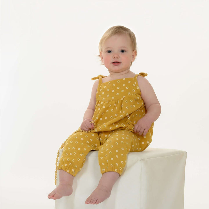 Schnittmuster Baby Mädchen Jumpsuit NELE PDF - Baby im gelben Overall mit Blumenmuster.