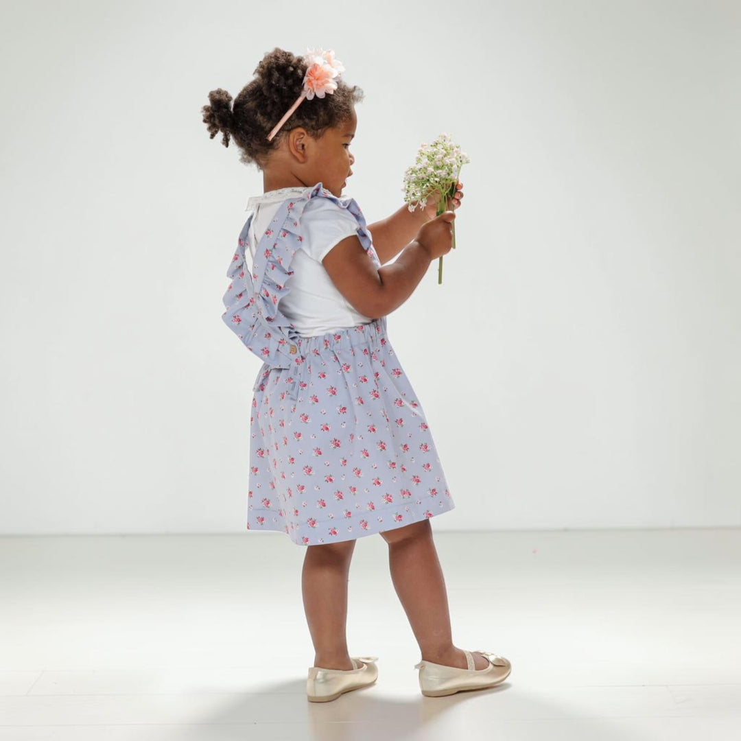 Latzkleid PDF Schnittmuster LIVIA – Rüschenkleid mit Trägern 68/74–116/122, kleines Mädchen mit Blumen im Kleid.