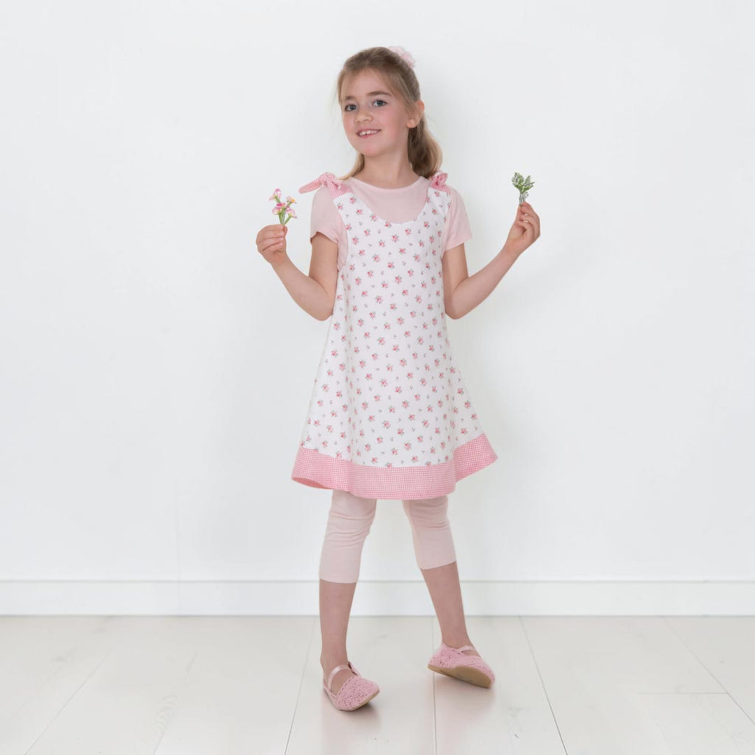 Trägerkleid PDF Schnittmuster ANTONIA – 3-in-1 Mädchenkleid 74/80–146/152, Mädchen trägt ein blumiges Kleid.