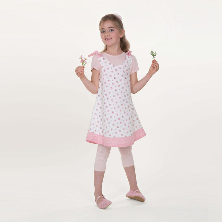 Mädchen trägt ein Tunika Kleid pdf Schnittmuster JULE ANTONIA STEFFI – 3-in-1 74/80–146/152 mit Blumenmuster und Schleifen.