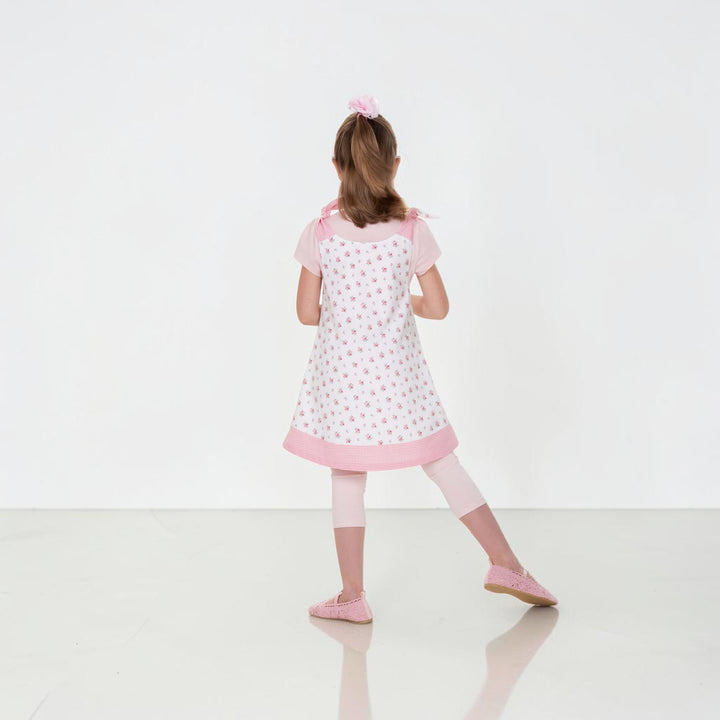 Mädchen trägt das Tunika Kleid pdf Schnittmuster JULE ANTONIA STEFFI – 3-in-1 74/80–146/152 in Rosa mit Blumenmuster.
