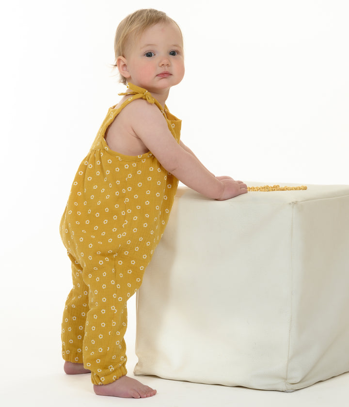 Schnittmuster Baby Overall NELE – Kleinkind in gelbem Overall mit Pünktchen, stehend an einem weißen Würfel.