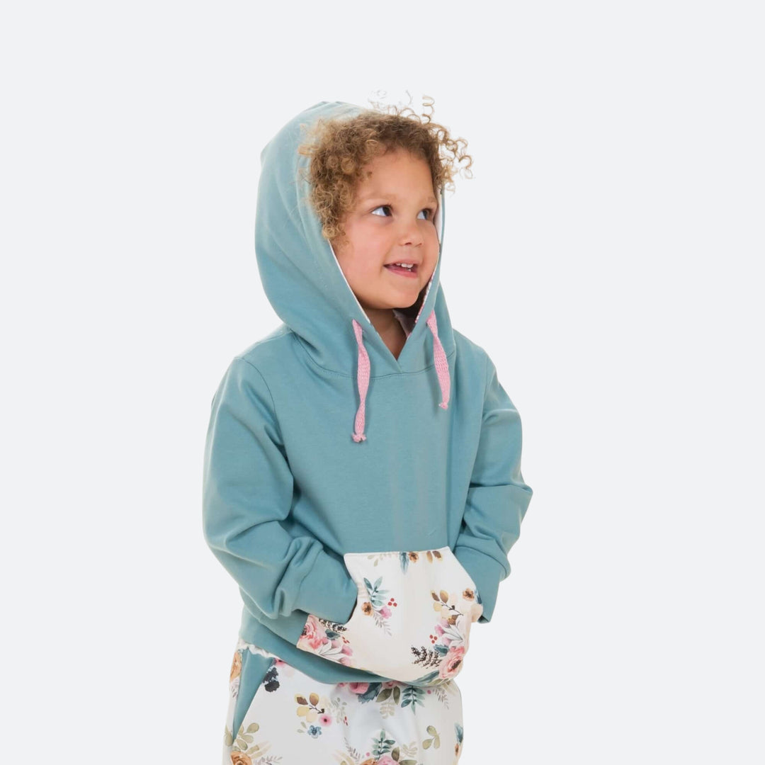 Kinder Hoodie PDF Schnittmuster FLY – 2-in-1 mit Kapuze & Kragen 80/86–140/146, Mädchen mit Kapuzenpullover in Türkis.