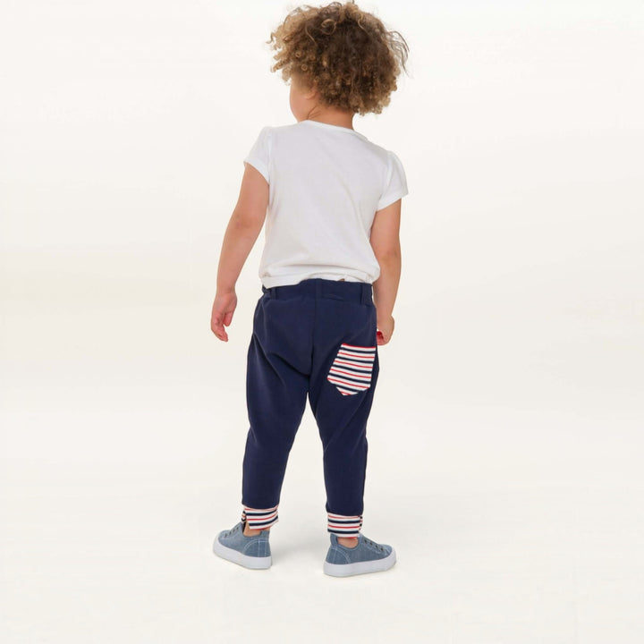Haremshose PDF Schnittmuster DADO – Baggy Kinderhose mit Taschen 92/98–140/146, Rückansicht eines Kindes in blauer Hose mit Streifen-Pocket.