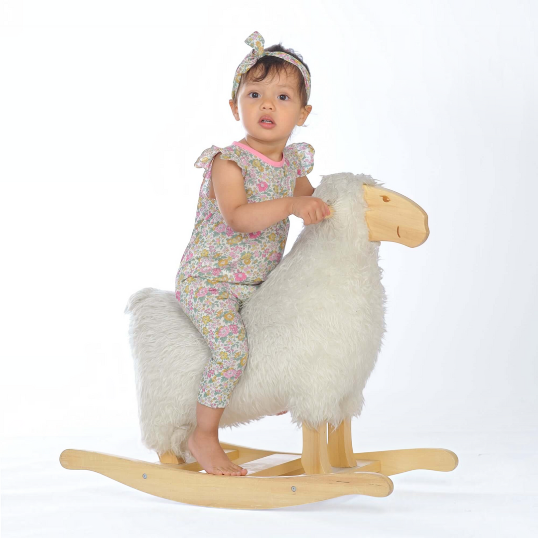 Schnittmuster Baby Overall MIA PDF - Kind in floral Overall auf einem Schaukel-Schaf.
