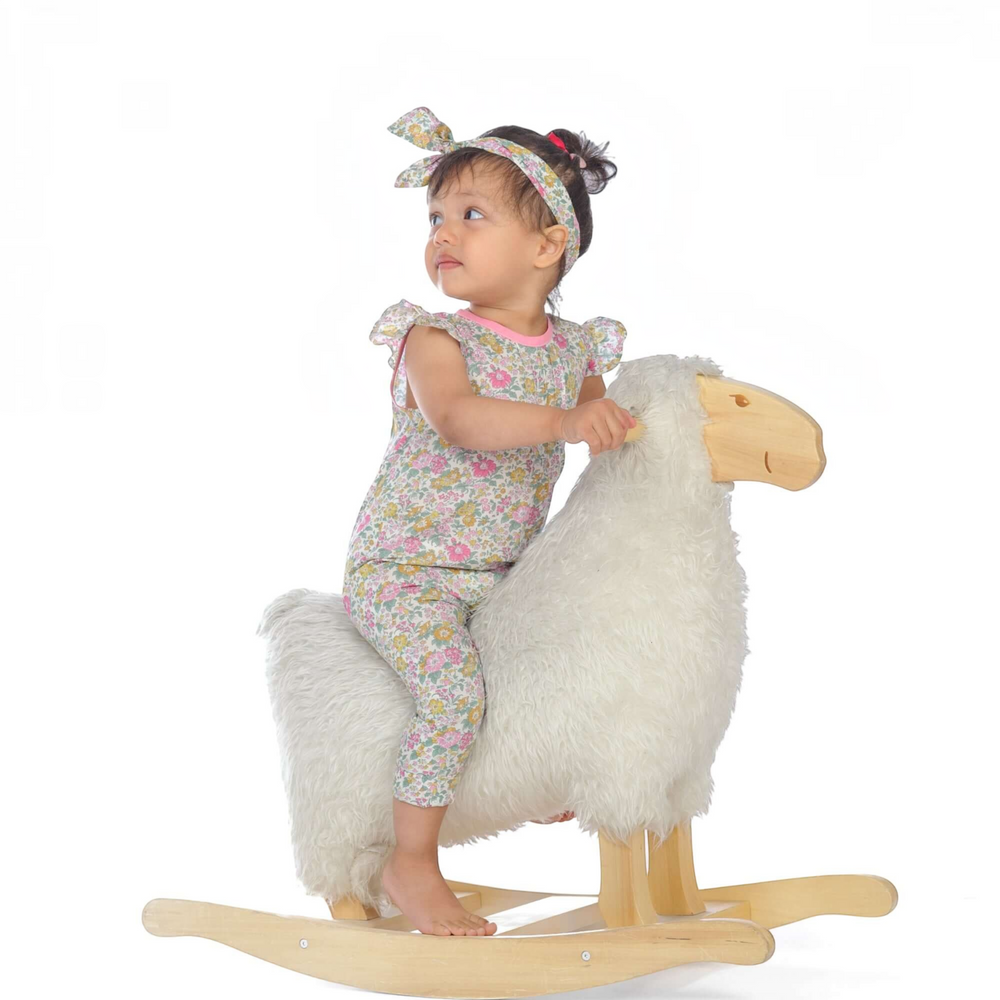 Schnittmuster Baby Overall MIA PDF - Baby in floral overall riding a rocking sheep toy with a headband.