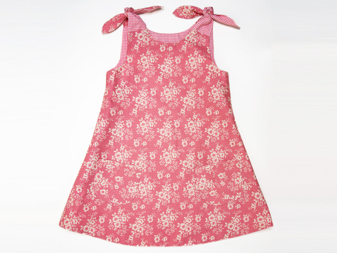 Schnittmuster Mädchenkleid STEFFI in rosa mit Blumenmuster und schulterlangen Bändern für Mädchen.