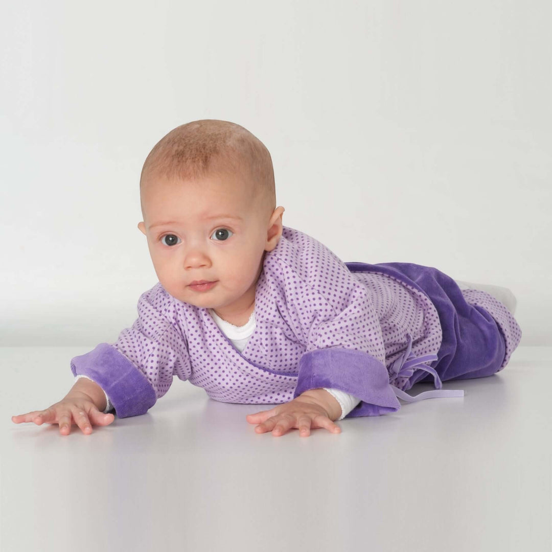 Babyjacke PDF Schnittmuster FIORINO – 3-in-1 Wickeljacke 50/56–86/92 – Baby in lila Wickeljacke auf dem Bauch liegend.