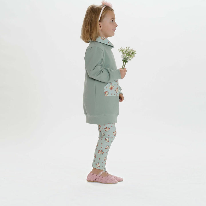 Kinder Hoodie PDF Schnittmuster ARWEN – Tunika mit Kapuze & Kragen 80/86–140/146, Mädchen in grünem Hoodie mit Blumenmuster.