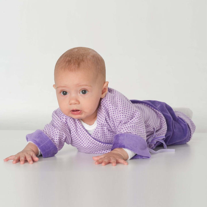 Babyjacke PDF Schnittmuster FIORINO – 3-in-1 Wickeljacke 50/56–86/92, Baby in lila Wickeljacke krabbelt auf dem Boden.