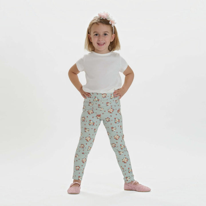 Mädchen in floral gemusterten Leggings und weißem T-Shirt, glücklich posierend, für Kinderbekleidung