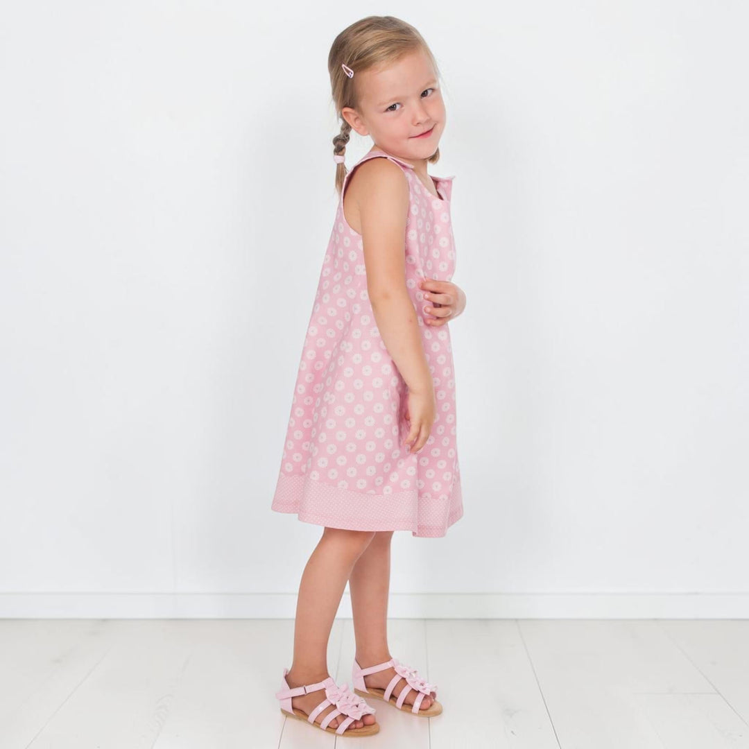 Mädchen trägt ein rosa Trägerkleid PDF Schnittmuster ANTONIA – 3-in-1 Mädchenkleid 74/80–146/152 mit Punkten und Bändern.