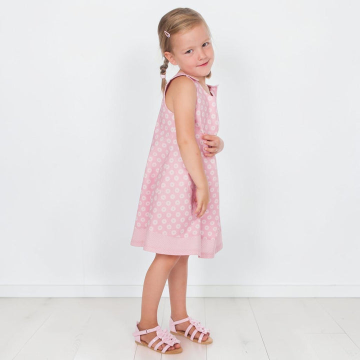 Mädchen trägt ein rosa Trägerkleid PDF Schnittmuster ANTONIA – 3-in-1 Mädchenkleid 74/80–146/152 mit Punkten und Bändern.