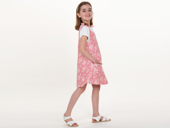 Schnittmuster Mädchenkleid STEFFI Gr. 74 - 152 präsentiert ein pinkes Kleid mit Blumenmuster, perfekt für den Sommer.