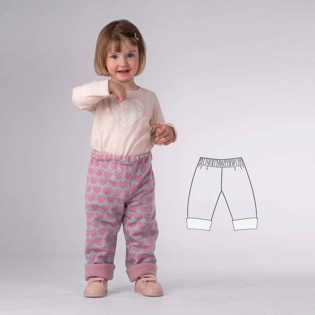 Kinder Wendehose PDF Schnittmuster FIOCCO – gefüttert 74/80–134/140 auf einem kleinen Mädchen mit Herzmotiv-T-Shirt und gemusterten Hosen.