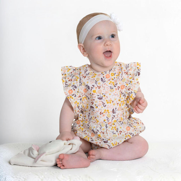Patternforkids Baby Mädchen Bloomer CHIARA aus geblümtem Stoff mit Rüschenärmeln, getragen von einem Baby