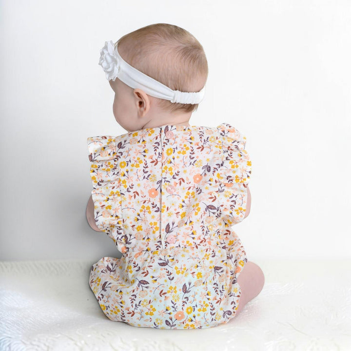 Patternforkids Baby Bloomer CHIARA aus geblümtem Musselin mit Rüschenärmeln an einem Baby von hinten