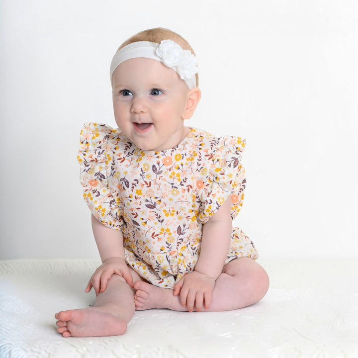 Patternforkids Baby Mädchen Bloomer CHIARA mit Blumenmuster und Rüschenärmeln an einem lächelnden Baby