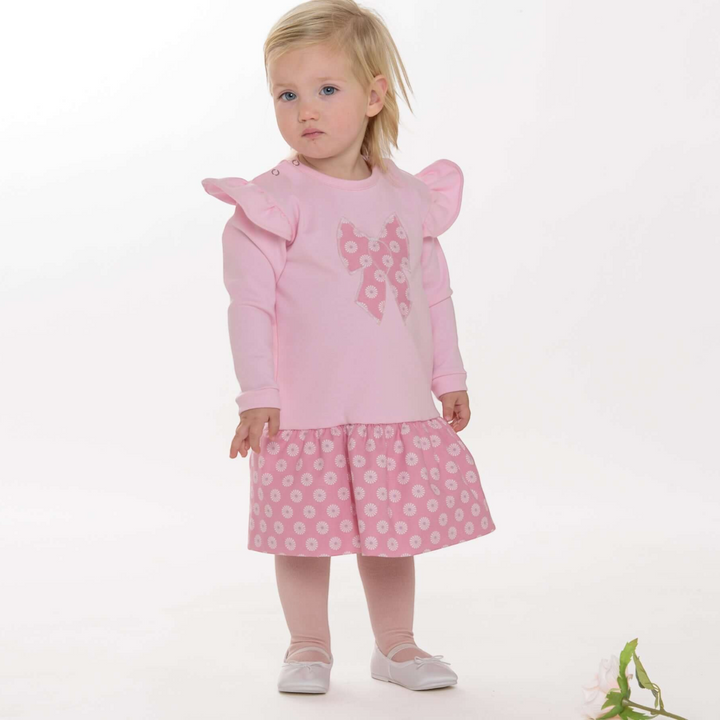 Kleinkind trägt ein Patternforkids Kleid mit rosa Oberteil, Rüschen an den Schultern und geblümtem Rock
