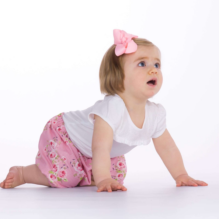 Kleinkind krabbelt in Patternforkids Pumphose Stella mit rosa Blumenmuster und elastischen Beinabschlüssen