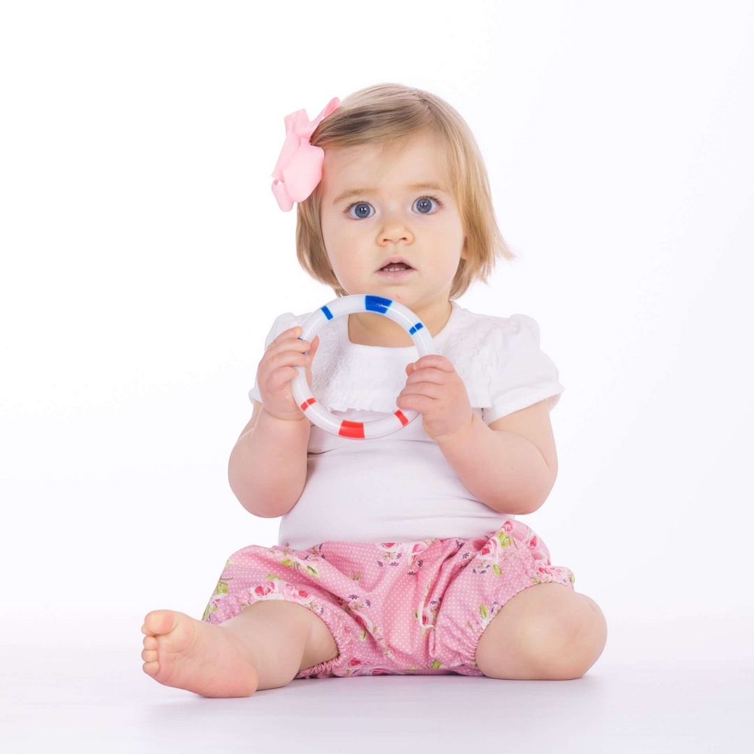 Patternforkids Baby Pumphose Stella Schnittmuster als rosa geblümte Bloomers an einem sitzenden Baby mit Spielzeug