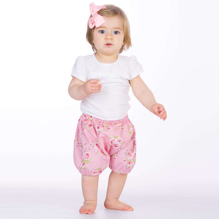 Kleinkind trägt eine rosa geblümte Patternforkids Pumphose Stella mit elastischen Beinabschlüssen und weißem Shirt