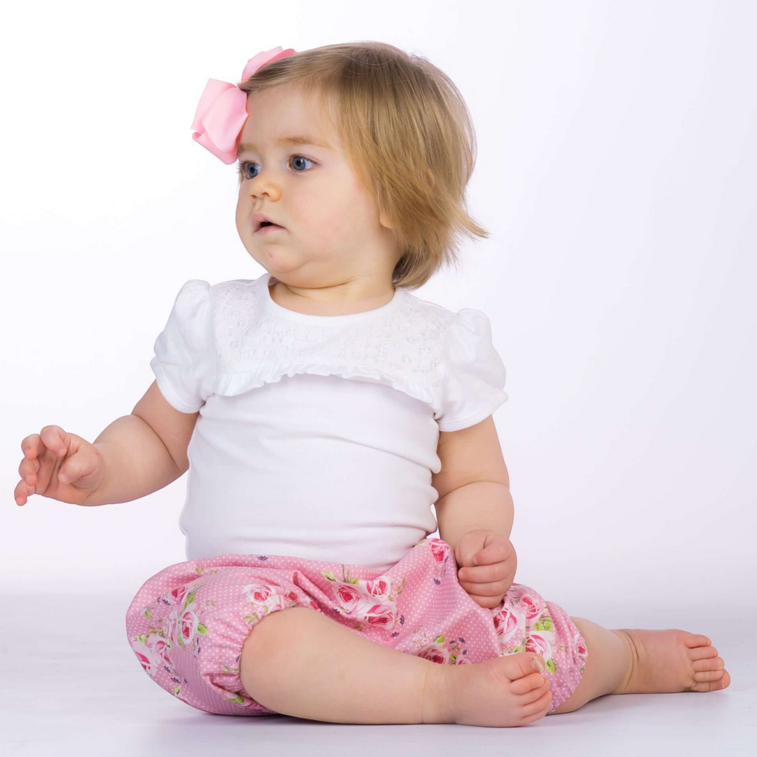 Kleinkind trägt eine rosa geblümte Patternforkids Pumphose Stella mit elastischen Beinabschlüssen beim Sitzen
