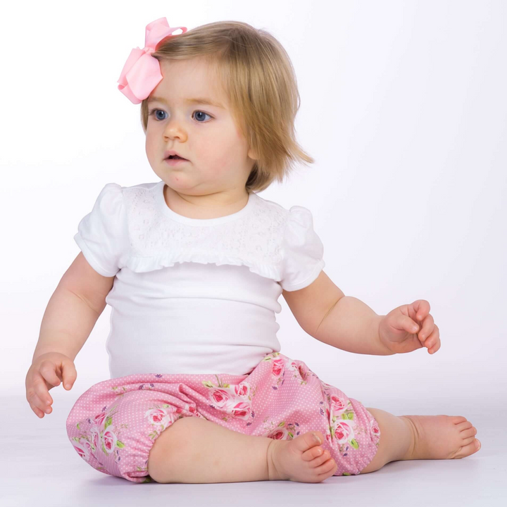 Kleinkind trägt eine rosa geblümte Patternforkids Pumphose STELLA mit elastischen Beinabschlüssen auf weißem Hintergrund