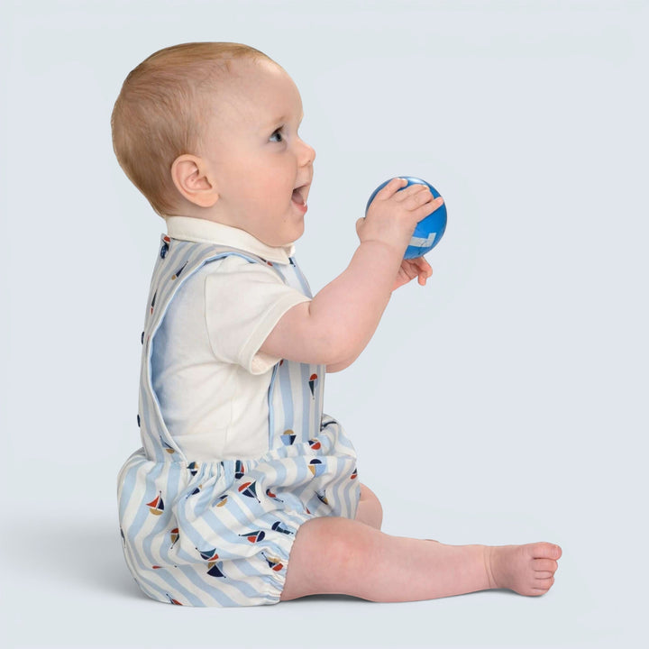 Patternforkids Baby Strampler MARCO als gestreifter Bloomer mit Segelboot-Muster, getragen von einem sitzenden Baby.
