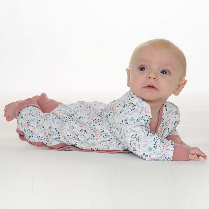 Patternforkids Baby Strampler LISA mit Blumenmuster und rosa Bündchen, liegendes Baby in fußlosem Langarm-Einteiler