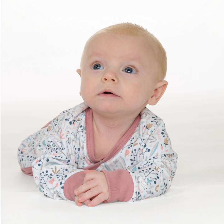 Patternforkids Baby Strampler LISA mit floralem Muster, langen Ärmeln und weichen rosa Bündchen in Bauchlage