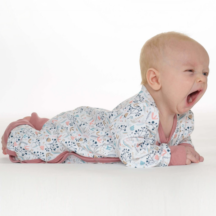 Patternforkids Baby Strampler LISA mit floralem Muster, langen Ärmeln und rosa Bündchen, getragen von einem gähnenden Baby