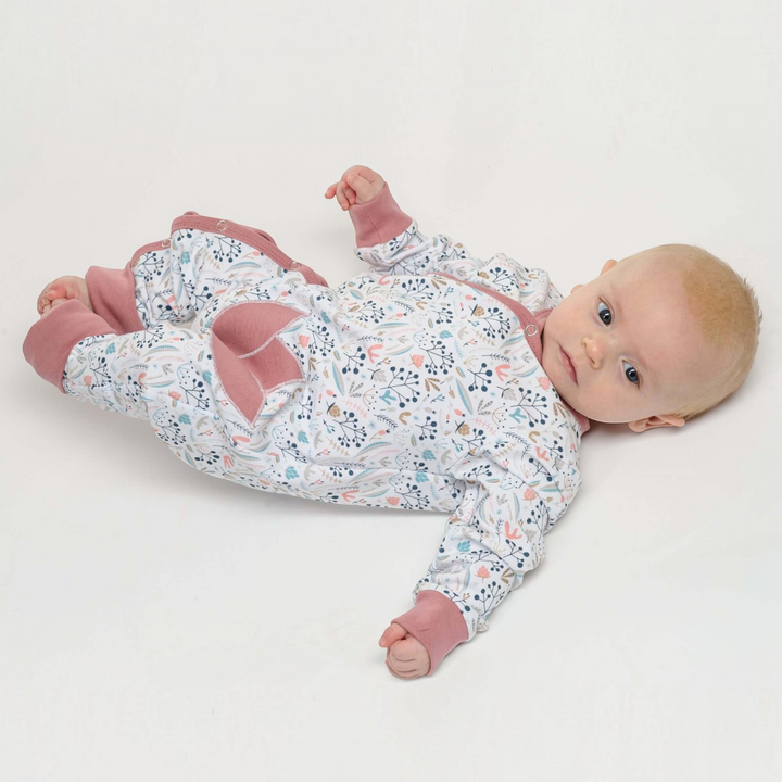 Patternforkids Baby Strampler LISA mit floralem Muster, langen Ärmeln und rosa Bündchen, getragen von einem Baby.