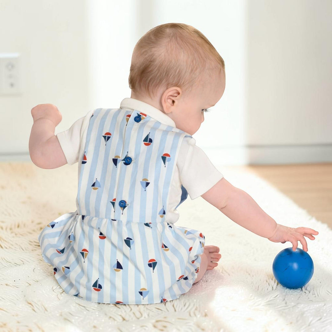 Patternforkids Baby Strampler MARCO mit blau-weißem Streifenmuster und Segelboot-Motiv, getragen von einem Baby.