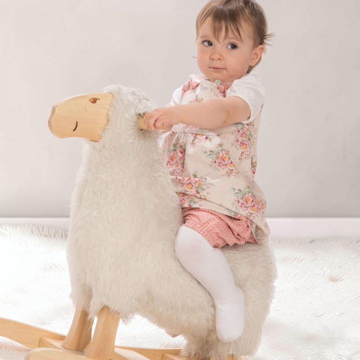 Patternforkids Baby Twinset mit Blumenkleid und Pumphose, getragen von einem Kind auf einem Schaukel-Schaf.