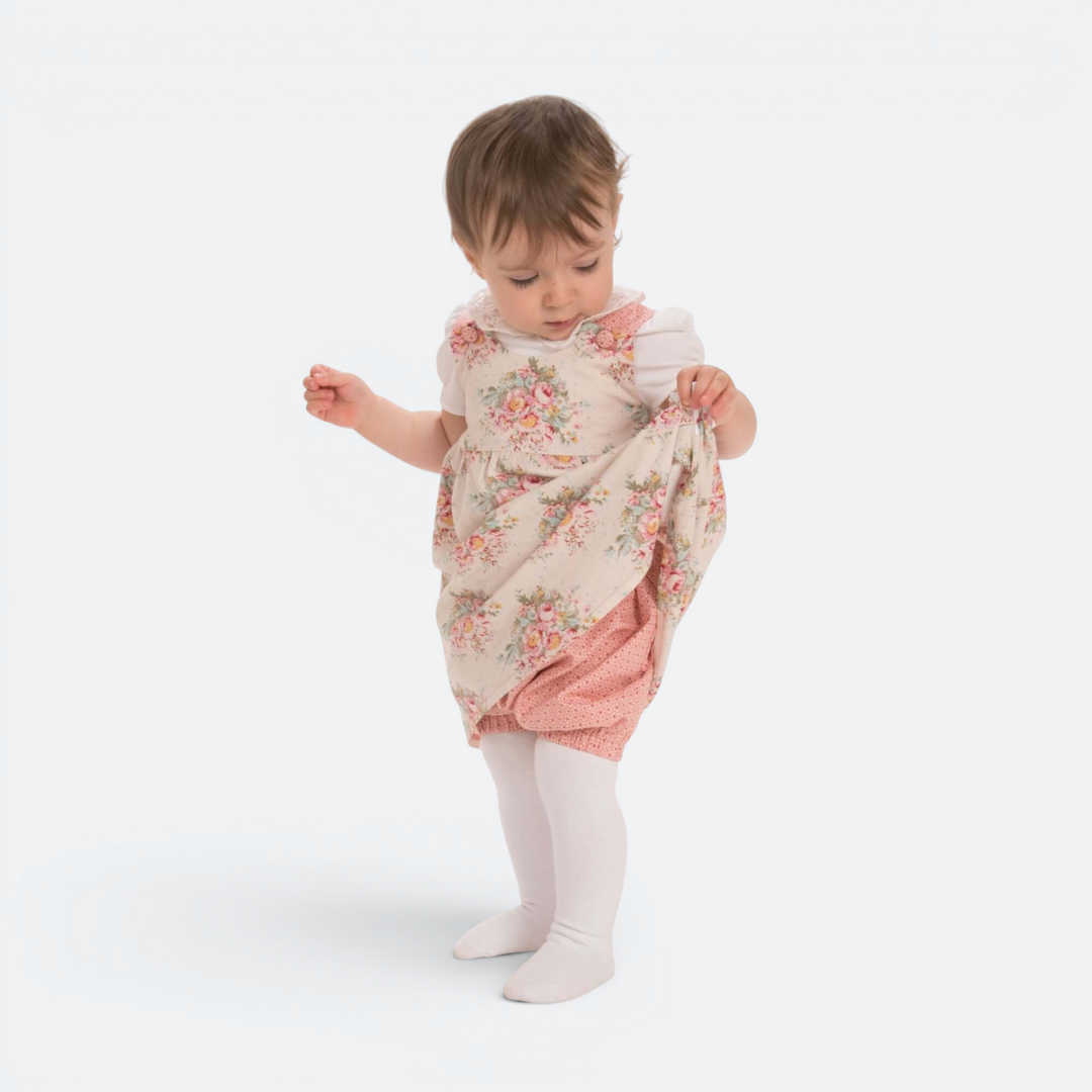 Patternforkids Baby Twinset CLARA mit geblümtem Kleid und rosa Pumphose an einem Kleinkind auf weißem Hintergrund