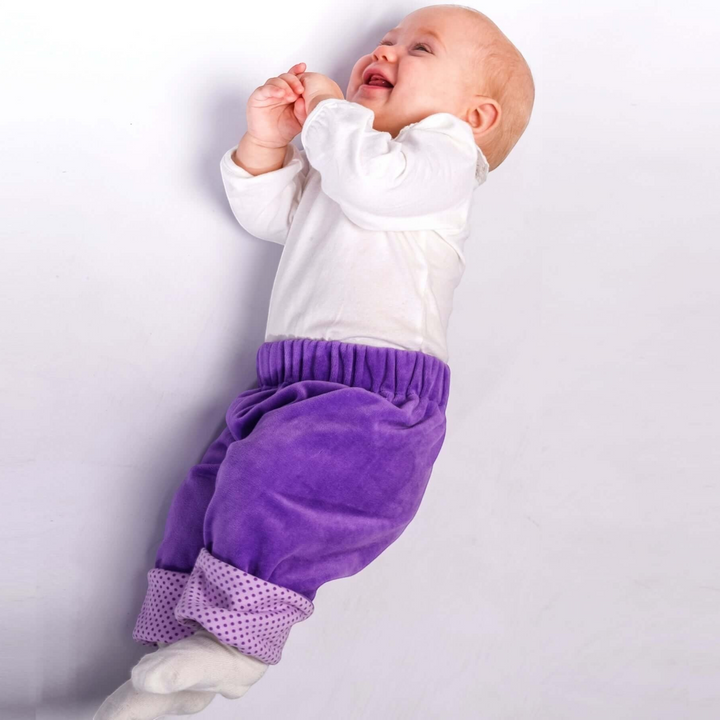 Patternforkids Baby Wendehose FIORETTO in Lila mit gepunkteten Bündchen, getragen von einem lachenden Baby.