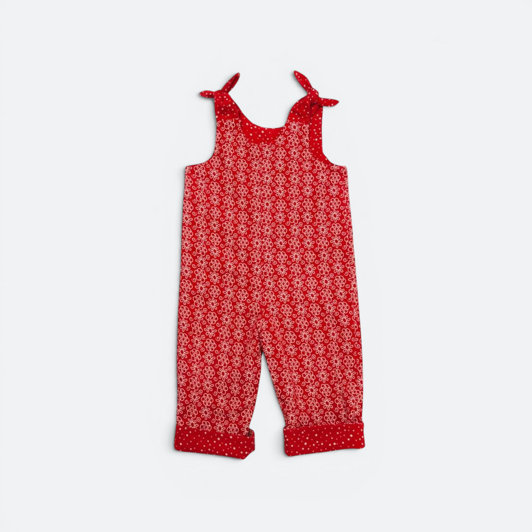 Patternforkids LILLI BO Baby-Wendeoverall in Rot mit Blumenmuster, Bindeschleifen und umgeschlagenen Beinsäumen.