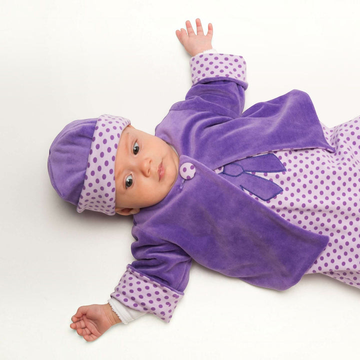 Patternforkids Babyjacke FILIPPA aus lila Velours mit gepunktetem Futter und passender Mütze an einem Baby