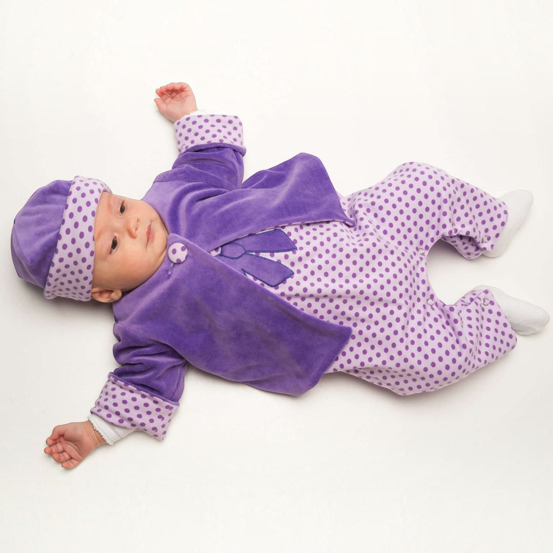 Patternforkids Babyjacke FILIPPA aus lila Velours mit gepunktetem Futter und passender Mütze an einem Baby