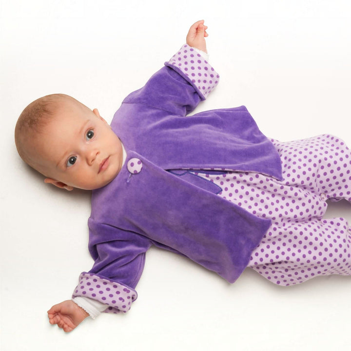 Patternforkids Babyjacke FILIPPA aus violettem Nicki mit gepunktetem Futter und Umschlagbündchen an einem Baby
