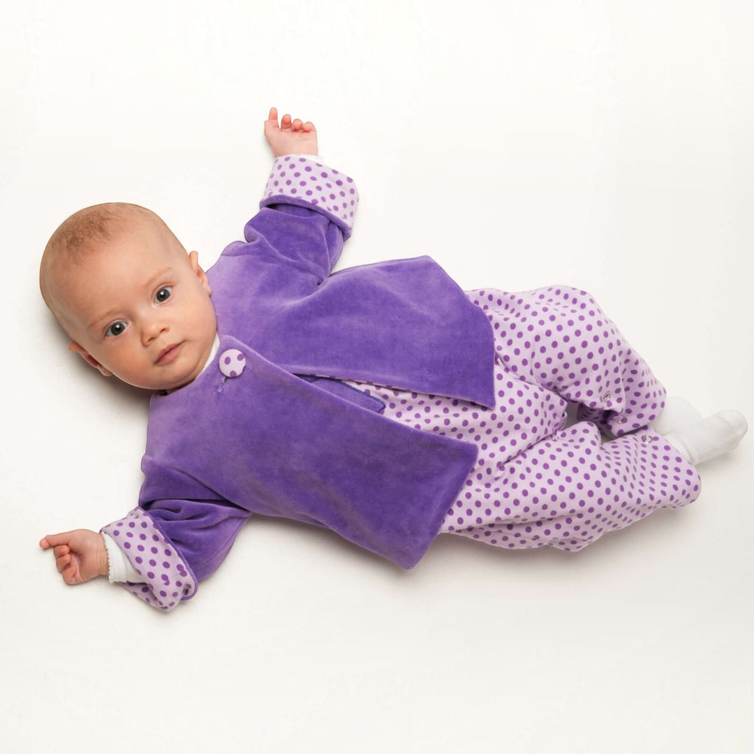 Patternforkids Babyjacke FILIPPA aus violettem Samt mit gepunktetem Futter und Armumschlägen an einem Baby