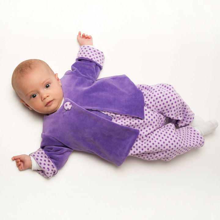 Patternforkids Babyjacke FILIPPA aus violettem Samt mit gepunktetem Futter und Armumschlägen an einem Baby