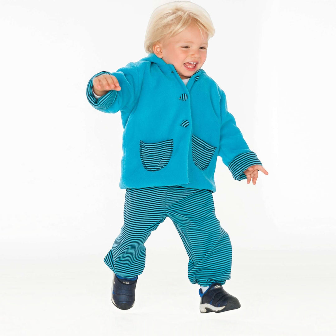 Patternforkids Babyjacke Toretto aus blauem Fleece mit Zipfelkapuze und gestreiften Taschen an einem lachenden Kind