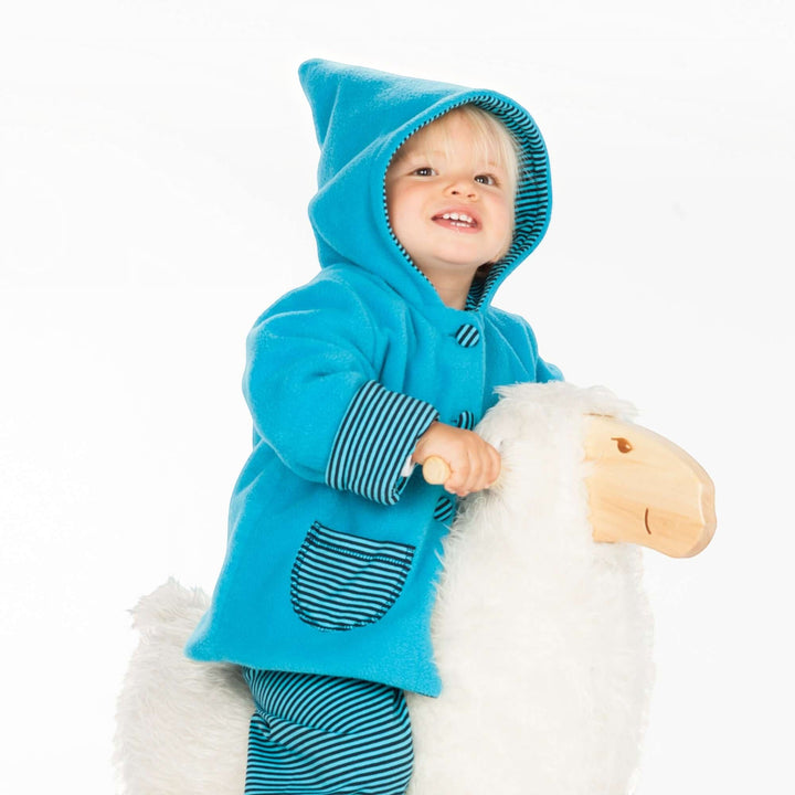 Patternforkids Babyjacke Toretto aus blauem Fleece mit Zipfelkapuze und gestreiften Details auf einem Schaukelpferd