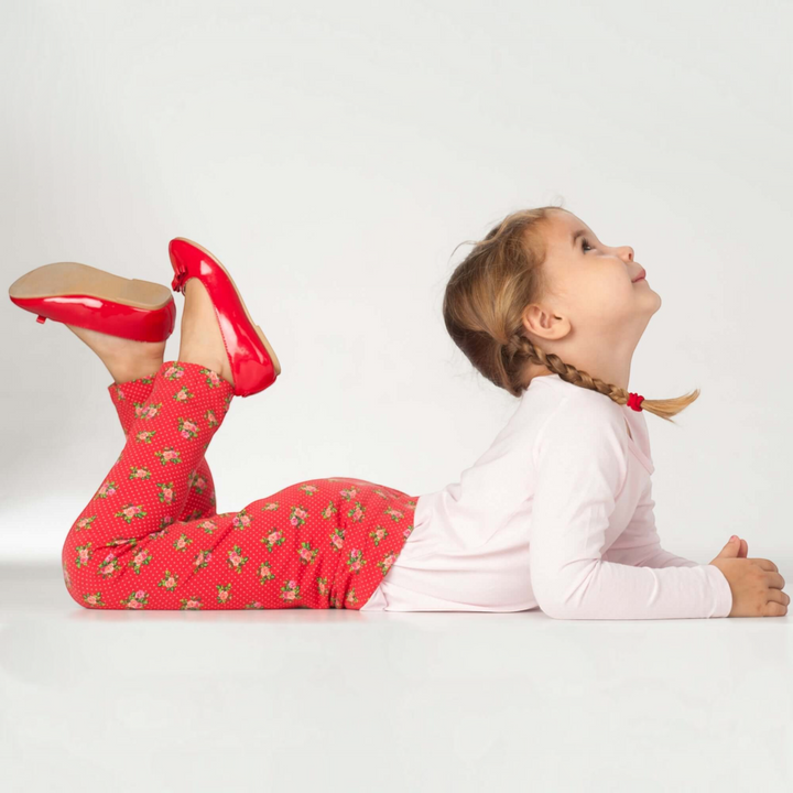 Patternforkids Schnittmuster Enna Leggings für Kinder aus rotem Blumen-Jersey, getragen von einem Mädchen beim Spielen.