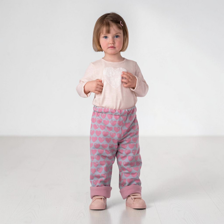 Patternforkids Schnittmuster Set Mara und Fiocco: Kleinkind trägt ein hellrosa Langarmshirt und eine gemusterte Hose.