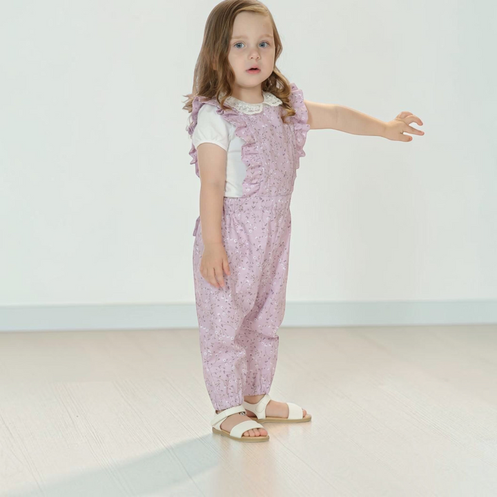 Patternforkids Latzhose DAISY mit Rüschen in zartem Flieder mit Blumenmuster an einem kleinen Mädchen